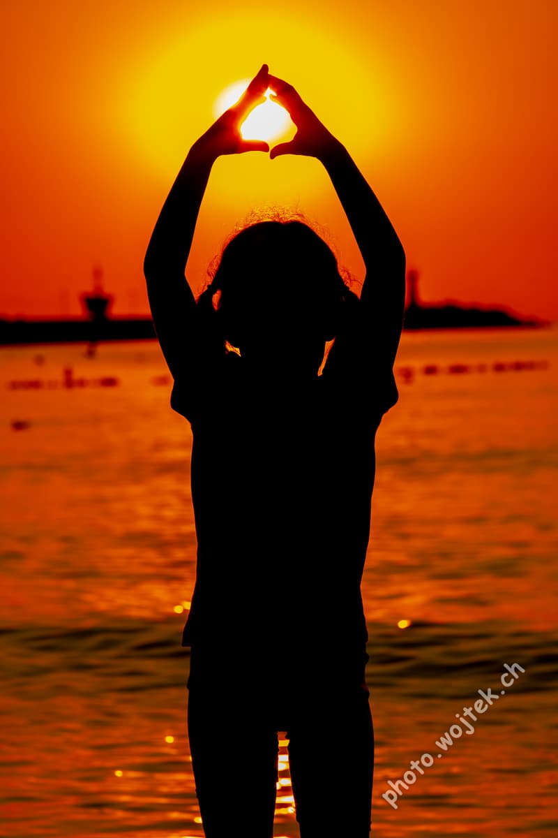Child silhouette holding sun at sunset Kolobrzeg Poland