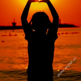 Child silhouette holding sun at sunset Kolobrzeg Poland