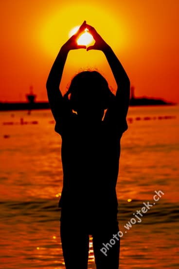 Child silhouette holding sun at sunset Kolobrzeg Poland