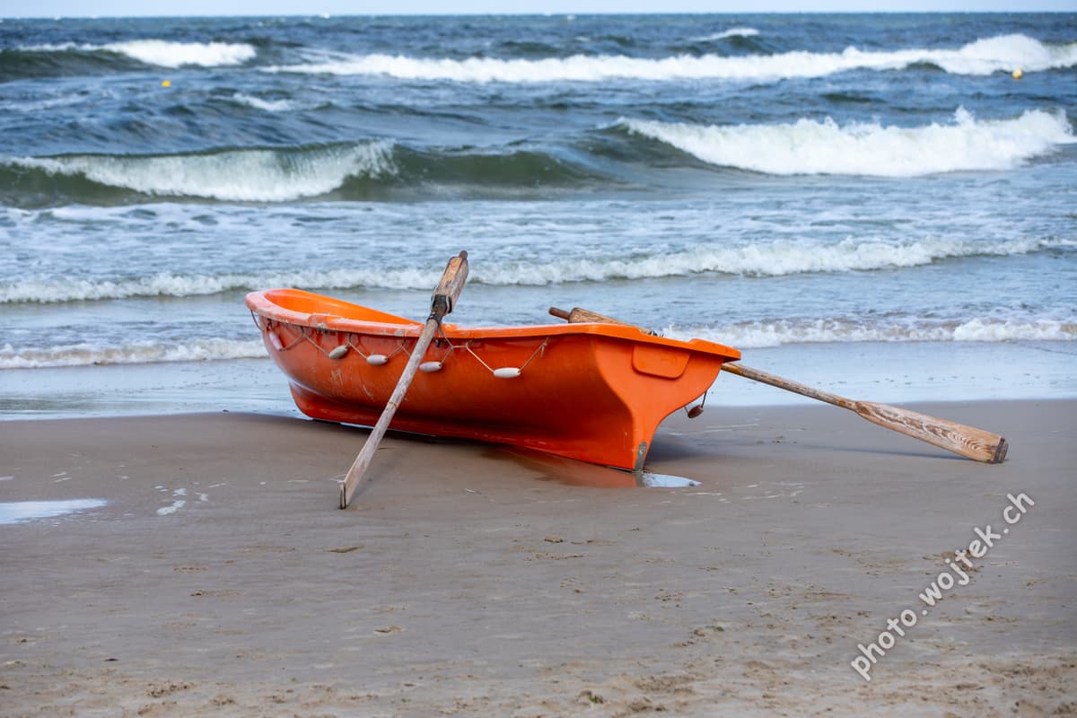 Orange rowboat on beach Kolobrzeg Poland