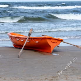 Orange rowboat on beach Kolobrzeg Poland