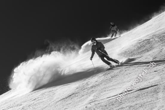 Skiers carving powder slope Schladming Austria